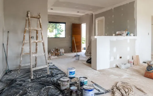 Antes: a sala em obra, com escada de madeira, latas de tinta e paredes em massa corrida